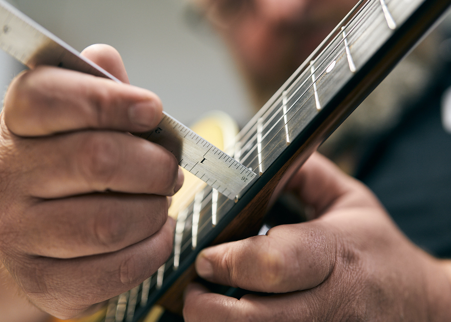 Person measuring string height on a guitar